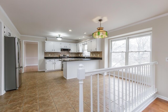 kitchen with white cabinetry, appliances with stainless steel finishes, crown molding, and backsplash