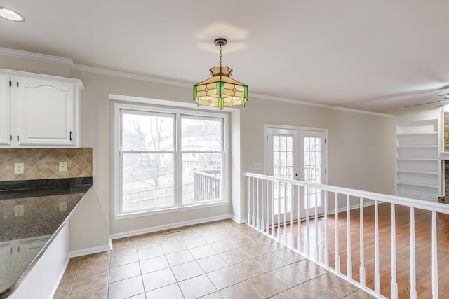 unfurnished dining area with french doors, ceiling fan, ornamental molding, and light tile patterned floors