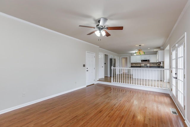 unfurnished living room with crown molding, ceiling fan, sink, and light hardwood / wood-style flooring