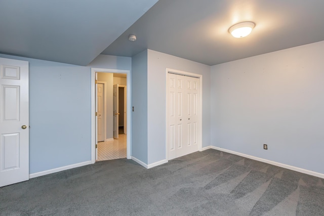 unfurnished bedroom with dark colored carpet and a closet