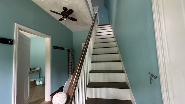 stairway with hardwood / wood-style floors, ceiling fan, and a textured ceiling