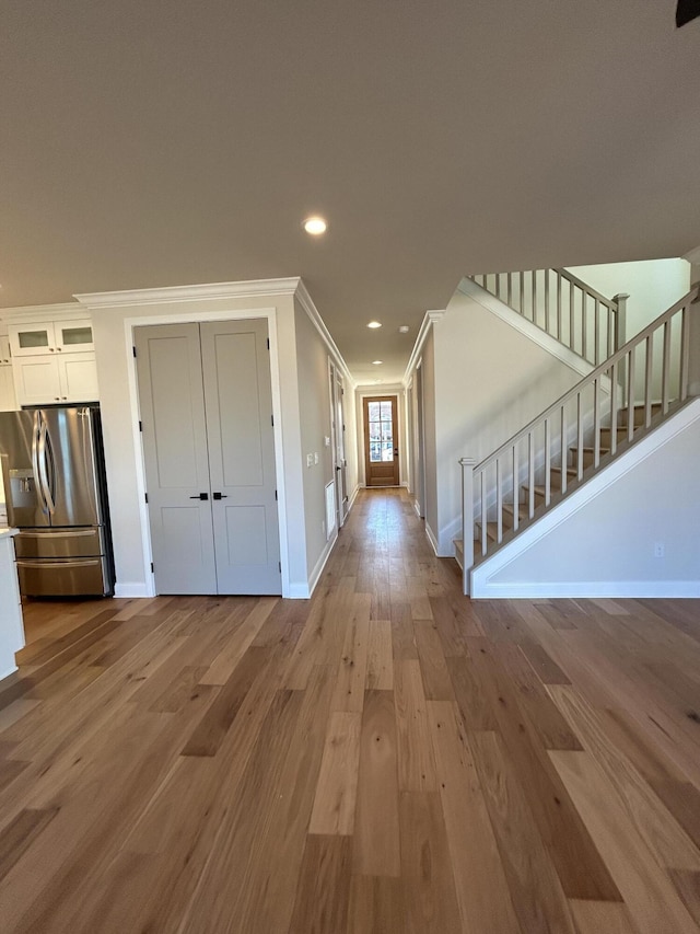 entrance foyer with recessed lighting, ornamental molding, light wood-style floors, baseboards, and stairs