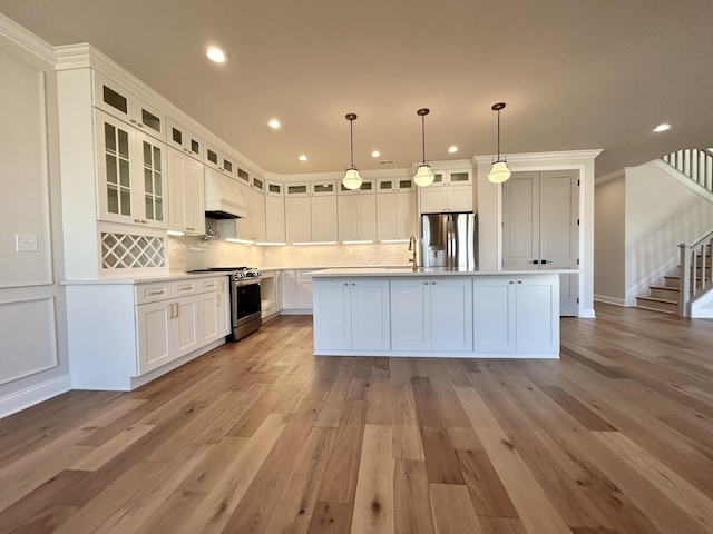 kitchen with white cabinetry, stainless steel appliances, backsplash, and light countertops