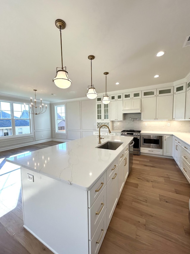 kitchen with tasteful backsplash, wood finished floors, stainless steel appliances, white cabinetry, and a sink