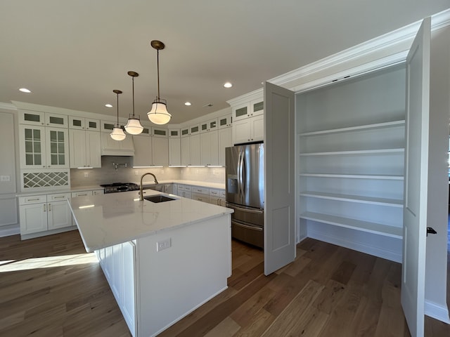 kitchen featuring dark wood-style floors, a kitchen island with sink, a sink, and stainless steel refrigerator with ice dispenser