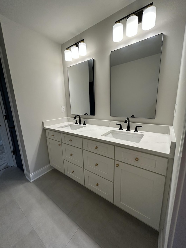 full bath featuring double vanity, tile patterned floors, a sink, and baseboards