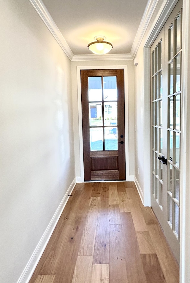 doorway featuring baseboards, ornamental molding, and wood finished floors