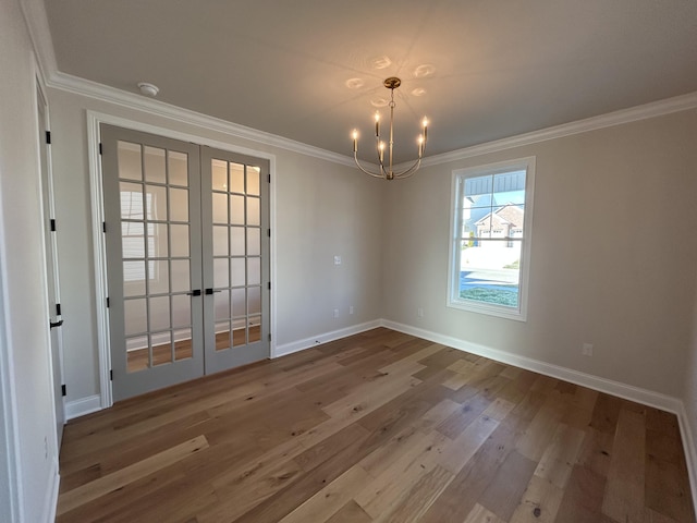 empty room featuring baseboards, wood finished floors, crown molding, and french doors