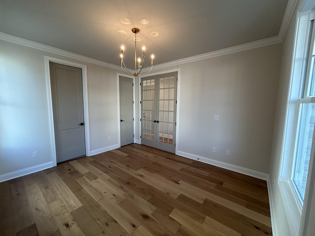 empty room with ornamental molding, french doors, wood finished floors, and baseboards