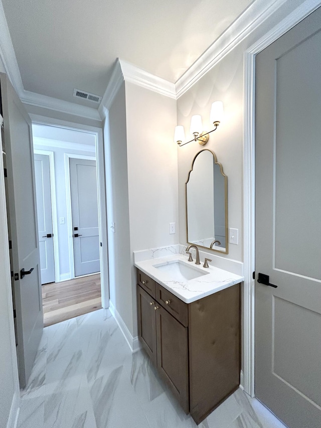 bathroom with marble finish floor, crown molding, visible vents, vanity, and baseboards