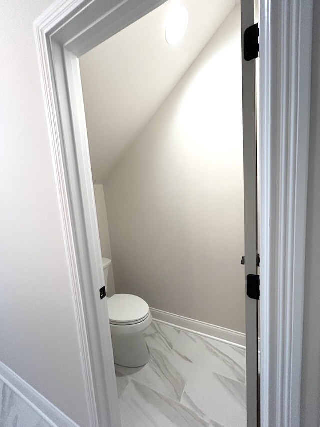 bathroom featuring toilet, marble finish floor, and baseboards