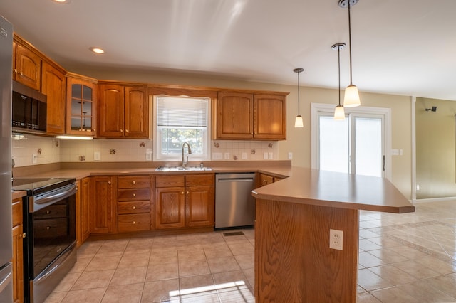 kitchen featuring sink, kitchen peninsula, decorative light fixtures, backsplash, and appliances with stainless steel finishes