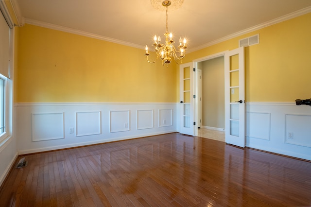 spare room with wood-type flooring, ornamental molding, and an inviting chandelier