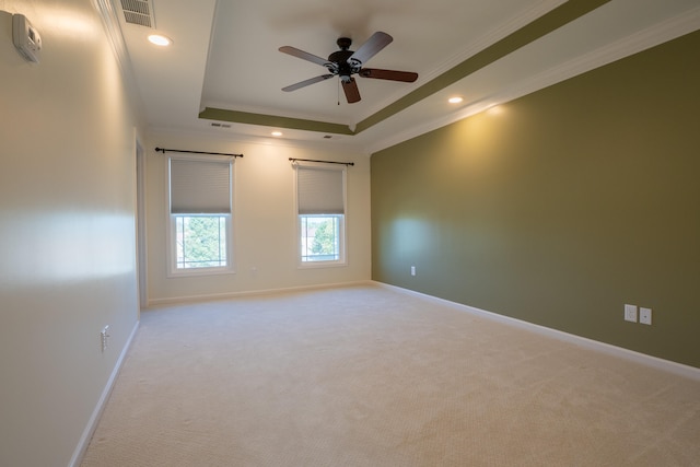 carpeted spare room featuring a tray ceiling, ceiling fan, and crown molding