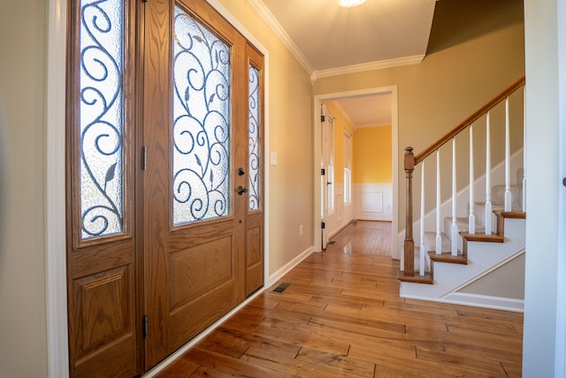 foyer entrance with ornamental molding and light hardwood / wood-style floors