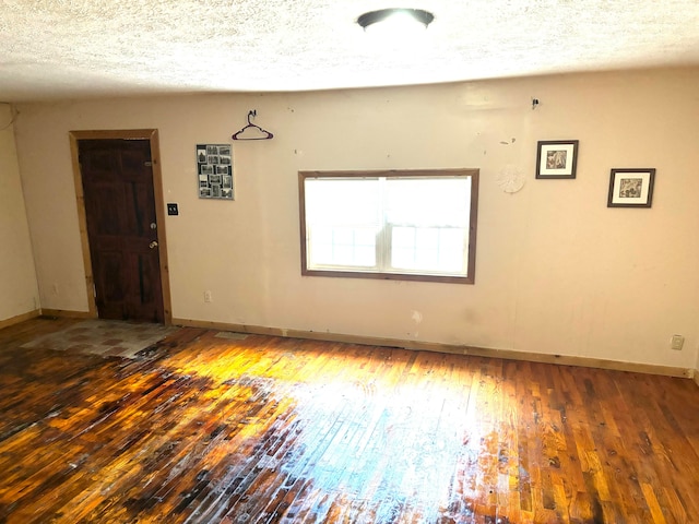 empty room with a textured ceiling and wood-type flooring