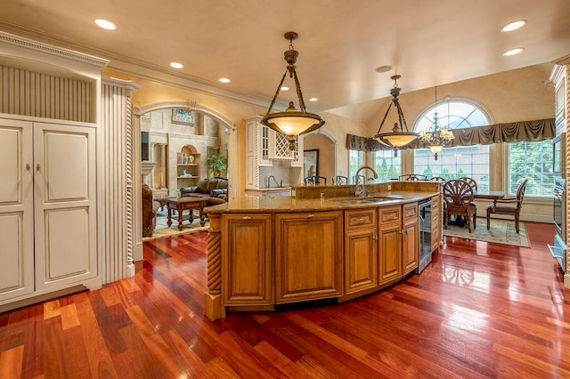 kitchen featuring sink, a center island with sink, decorative light fixtures, dark wood-type flooring, and an inviting chandelier