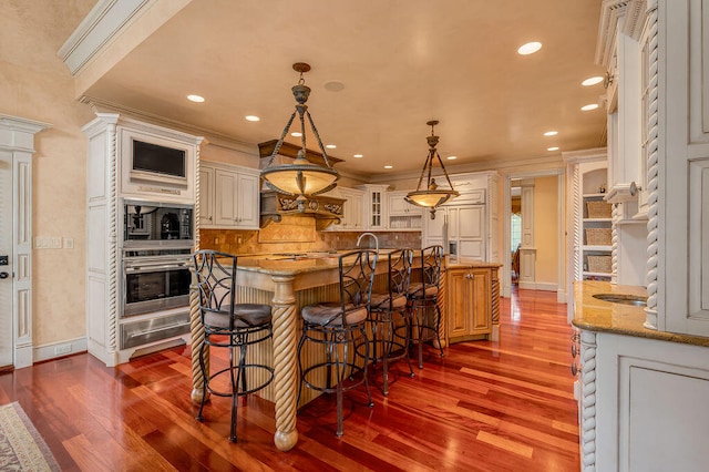 kitchen with pendant lighting, a center island, dark hardwood / wood-style flooring, light stone countertops, and stainless steel oven