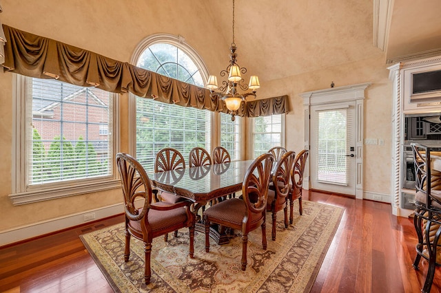 dining space with ornamental molding, dark wood-type flooring, and a chandelier