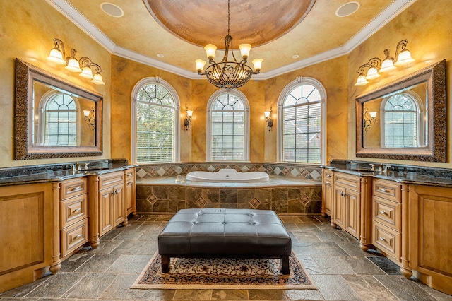 bathroom with tiled tub, vanity, a tray ceiling, and ornamental molding