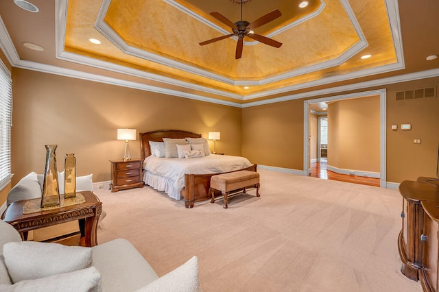 bedroom with ceiling fan, light colored carpet, a tray ceiling, and crown molding