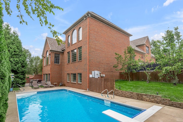 view of swimming pool featuring a patio, a diving board, and a yard