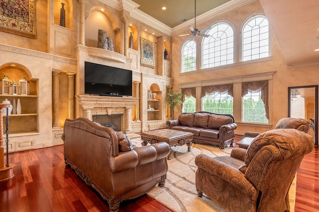 living room featuring ceiling fan, a towering ceiling, and wood-type flooring