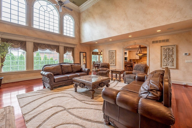 living room featuring ornamental molding, a high ceiling, ceiling fan, and hardwood / wood-style floors