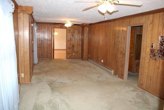 spare room with light colored carpet, ceiling fan, crown molding, a baseboard radiator, and wood walls