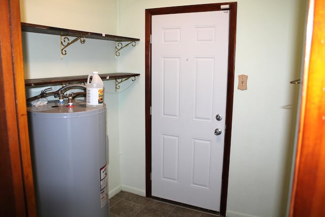 laundry area with dark tile patterned flooring and gas water heater