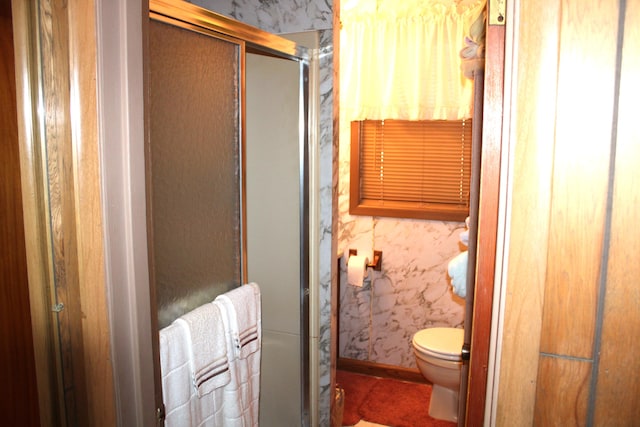 bathroom with a shower with shower door and toilet