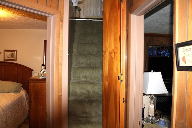 staircase featuring a textured ceiling and wood walls