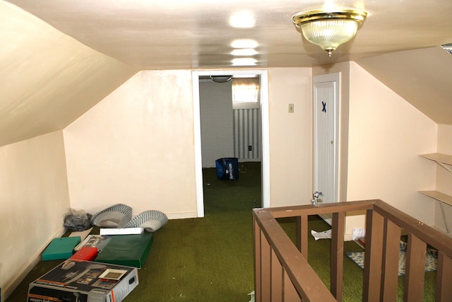 additional living space with dark colored carpet and vaulted ceiling