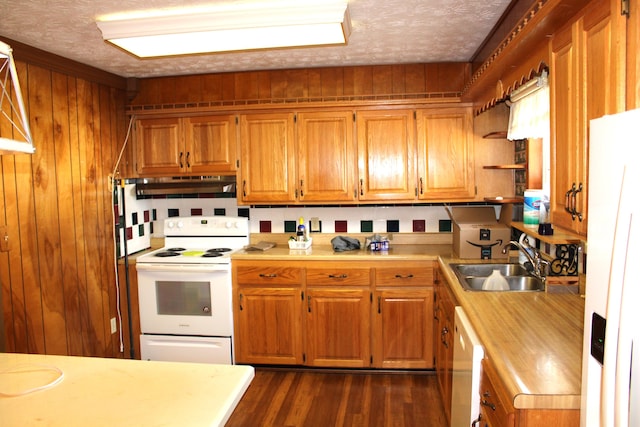 kitchen featuring tasteful backsplash, white appliances, wooden walls, sink, and dark hardwood / wood-style floors