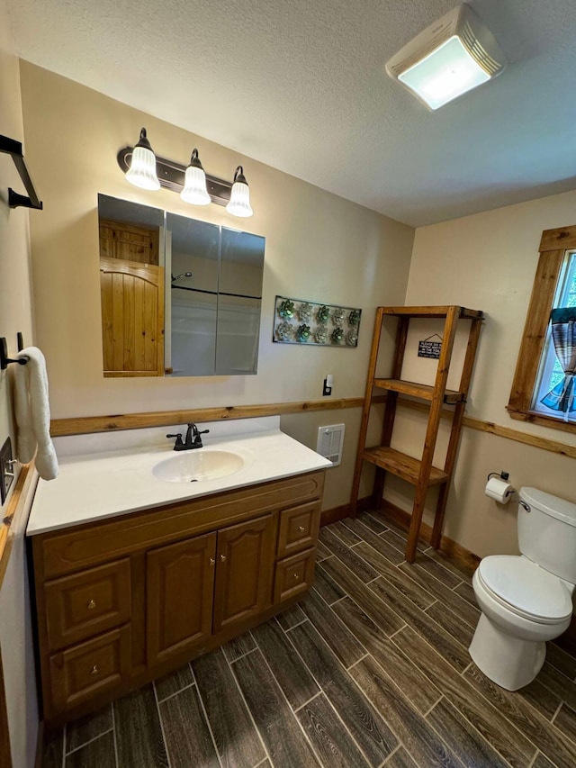 bathroom with wood-type flooring, a textured ceiling, vanity, and toilet