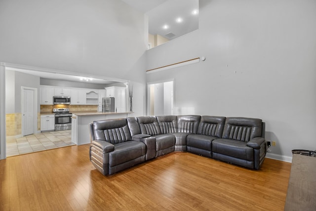 living room with light hardwood / wood-style floors and a towering ceiling