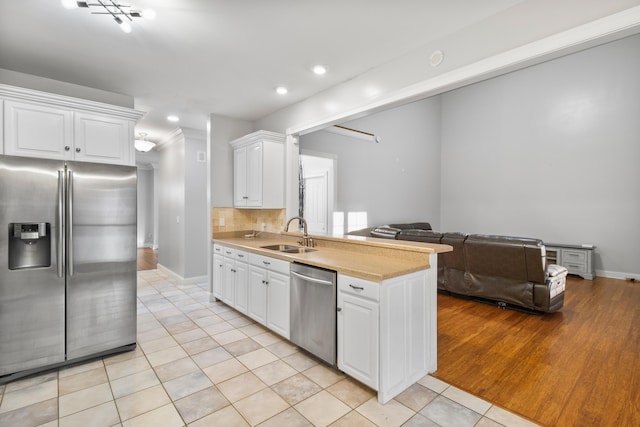 kitchen with white cabinets, sink, light tile patterned floors, appliances with stainless steel finishes, and tasteful backsplash