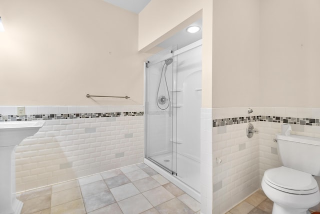 bathroom featuring tile patterned flooring, toilet, and tile walls