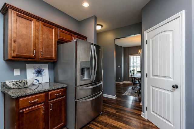 kitchen featuring dark stone counters, stainless steel fridge, and dark hardwood / wood-style floors