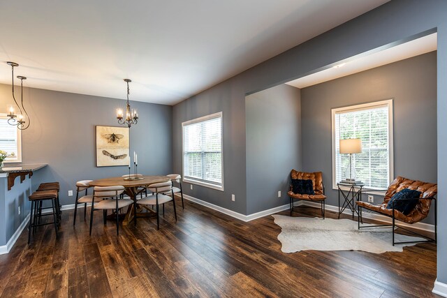 dining area featuring an inviting chandelier, a healthy amount of sunlight, and dark hardwood / wood-style flooring