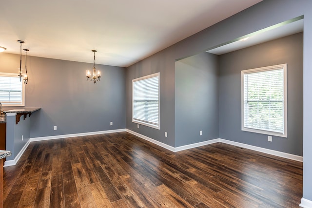 empty room featuring an inviting chandelier and dark hardwood / wood-style flooring