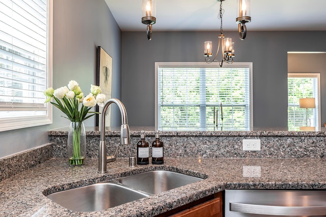 kitchen featuring decorative light fixtures, stone countertops, a healthy amount of sunlight, and sink