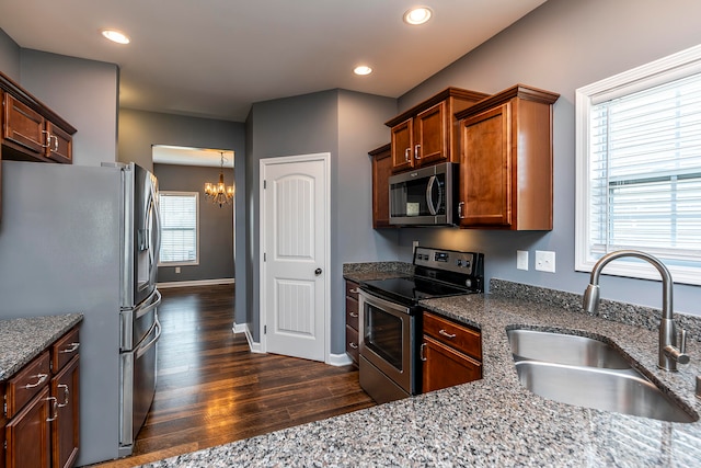 kitchen featuring a chandelier, dark wood-type flooring, sink, stainless steel appliances, and dark stone countertops