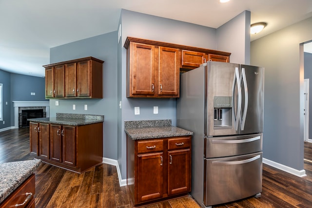 kitchen featuring stainless steel fridge, dark stone countertops, and dark hardwood / wood-style floors