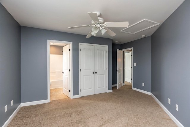 unfurnished bedroom with a closet, ceiling fan, light colored carpet, and ensuite bathroom