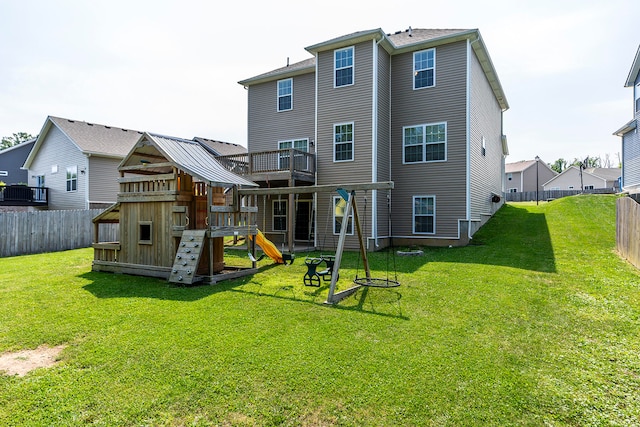 back of house featuring a playground and a yard