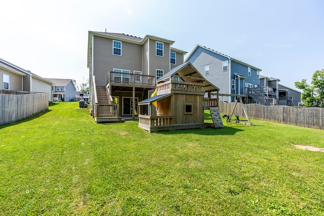 rear view of house with central AC unit, a deck, and a yard