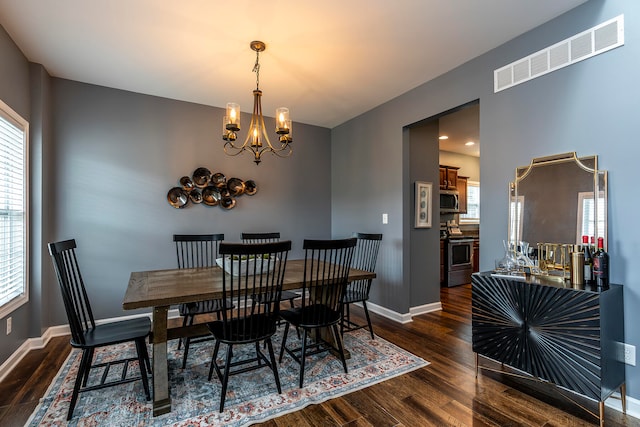 dining space with dark hardwood / wood-style floors and a chandelier