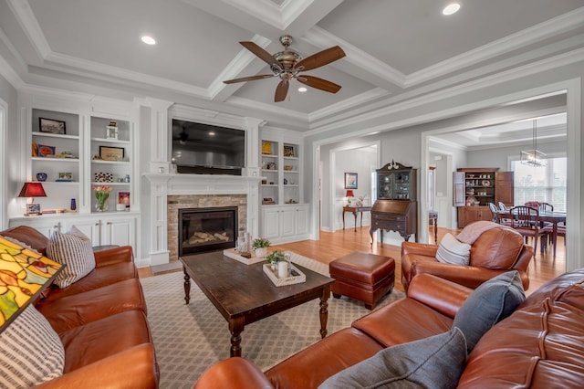 living area featuring beamed ceiling, light wood-style flooring, a fireplace, and crown molding