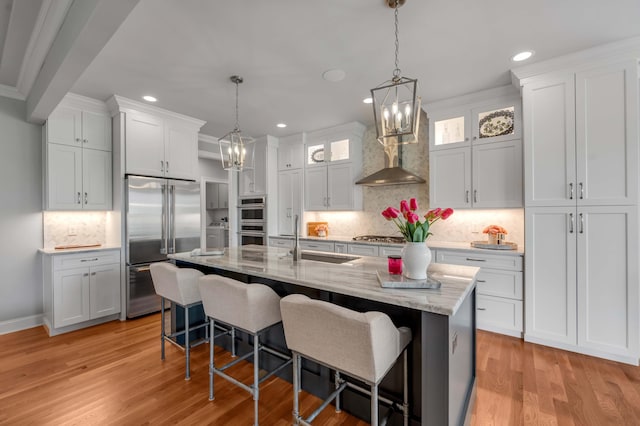 kitchen with a sink, stainless steel appliances, white cabinets, a kitchen breakfast bar, and light wood-type flooring